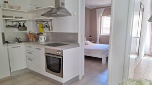 Een koffiezetapparaat/waterkoker, een koelkast, een oven, een kookplaat