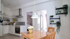 Een moderne keuken met witte kasten, een houten eettafel met stoelen, en een hangende吊灯.