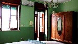 Una stanza con un letto grande, un armadio in legno, un lampadario e una finestra con tende.