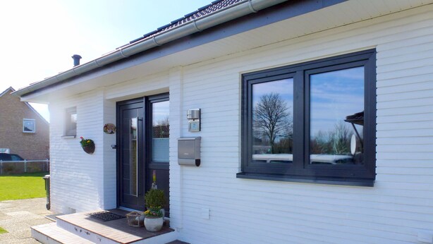 Ein modernes Haus mit einer Haustür, Stufen, einer kleinen Veranda und einem Fenster.