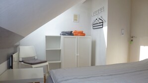 Ein Schlafzimmer mit Bett, Schreibtisch und Kleiderschrank.