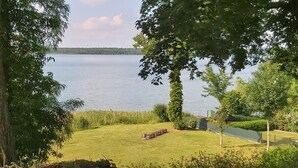 A lakeside view with a grassy area, a bench, and a building in the background.