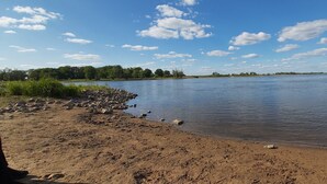 A riverbank with a sandy shore and scattered rocks.