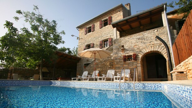 A stone building with a swimming pool, outdoor chairs, and an umbrella. - Istrian villa with swimming pool for an unforgettable holiday  (ZRENJ)