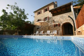 A stone building with a swimming pool, outdoor chairs, and an umbrella. - Istrian villa with swimming pool for an unforgettable holiday  (ZRENJ)