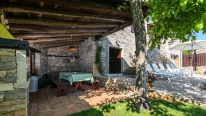 A stone building with a covered patio, outdoor seating, and a tree providing shade. - Istrian villa with swimming pool for an unforgettable holiday  (ZRENJ)