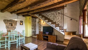 A rustic living room with a wooden staircase, a dining table with chairs, and a television on a wooden cabinet. - Istrian villa with swimming pool for an unforgettable holiday  (ZRENJ)