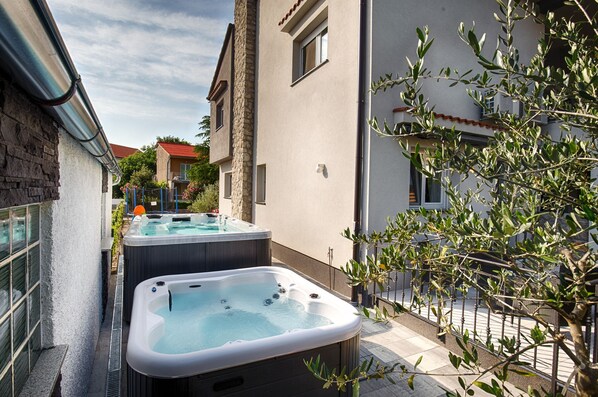 A spa area with two hot tubs and a stone wall.