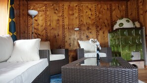 A wooden-paneled room with wicker furniture, a green cabinet, and a white lamp.
