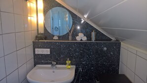 Une salle de bain avec un lavabo blanc, un miroir et un porte-serviettes.