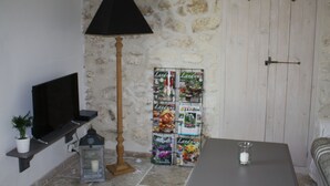 Een kamer met een televisie op een plank, een lamp, een tafel met een kaars, en een muur met een deur en decoraties in de vorm van harten.