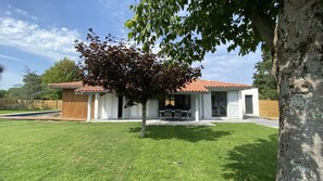 A house with a tiled roof, a covered patio, and a lawn.