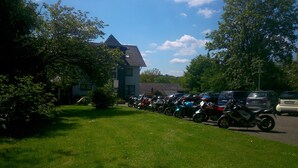 Una fila de motocicletas estacionadas en un área verde con un edificio al fondo.