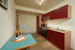 Eine kleine Küche mit roten Schränken, einer Holz Arbeitsplatte und einem Tisch mit Flaschen und Gläsern.
