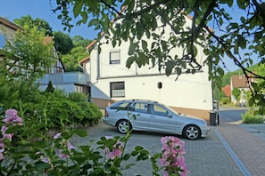 Une voiture argentée était garée devant une maison à deux étages, dont l’allée était pavée de briques.