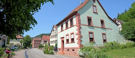 En traditionel bygning i europæisk stil med en markant gavl, flere vinduer og en murstensfacade.
