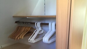 En garderob i trä med hyllor och plats för att hänga kläder.
