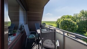 A balcony with a view of a green landscape and trees. - **** Apartment behind the dike (Westerdeichstrich)