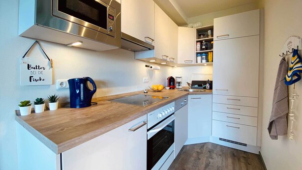 A modern kitchen with stainless steel appliances, white cabinetry, and a wooden countertop. - **** Apartment behind the dike (Westerdeichstrich)