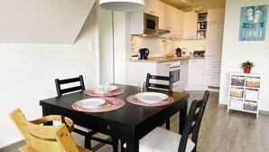 A dining area with a black table and chairs, a white pendant light, and a kitchen in the background. - **** Apartment behind the dike (Westerdeichstrich)
