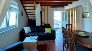 A cozy living room with a wooden ceiling, a sofa, a coffee table, and a dining area with a table and chairs. - Family-friendly country house Marie with heated pool, barbecue area, 5 persons (Krk)