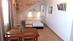 A small, cozy room with a wooden dining table, a bed with white linens, and a TV mounted on the wall. - Holiday apartment "Villa Bonaca" with a beautiful panoramic (Baska Voda)