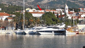 A marina with several yachts docked, a church with a bell tower, and residential buildings in the background. - Holiday apartment "Villa Bonaca" with a beautiful panoramic (Baska Voda)