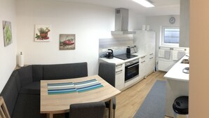 A compact kitchen with a dining area, a built-in oven, and a small window. - Wendlers Ferienwohnungen 4-6 (Schwaig bei Nuernberg)