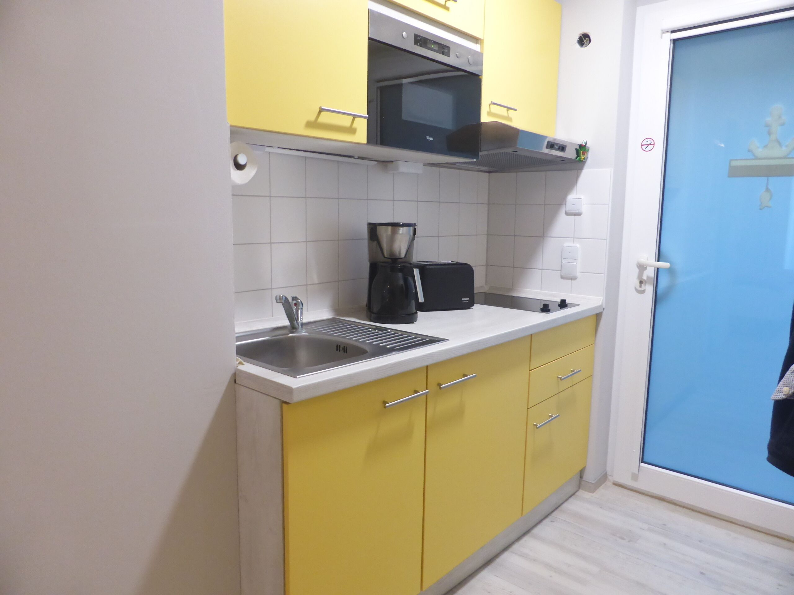 A compact kitchen with a sink, a coffee maker, and a toaster.