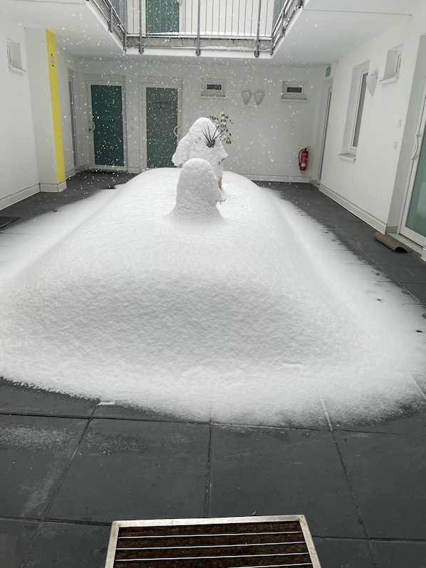 Ein großzügiger Innenbereich mit hoher Decke und Dachfenster, der durch einen großen, mit Schnee bedeckten Boden und einen an der Wand befestigten Feuerlöscher gekennzeichnet ist.