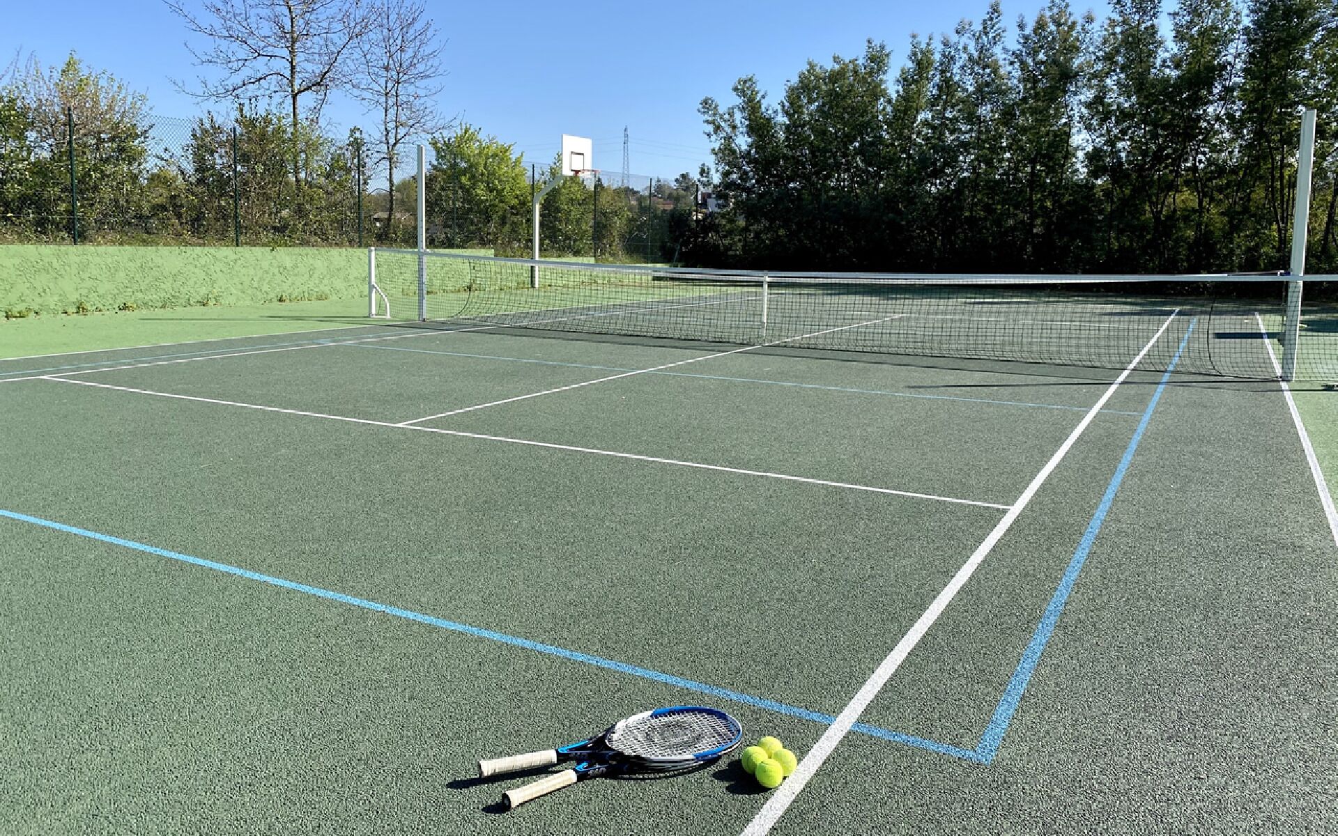 A tennis court with a net, lines, and tennis balls.