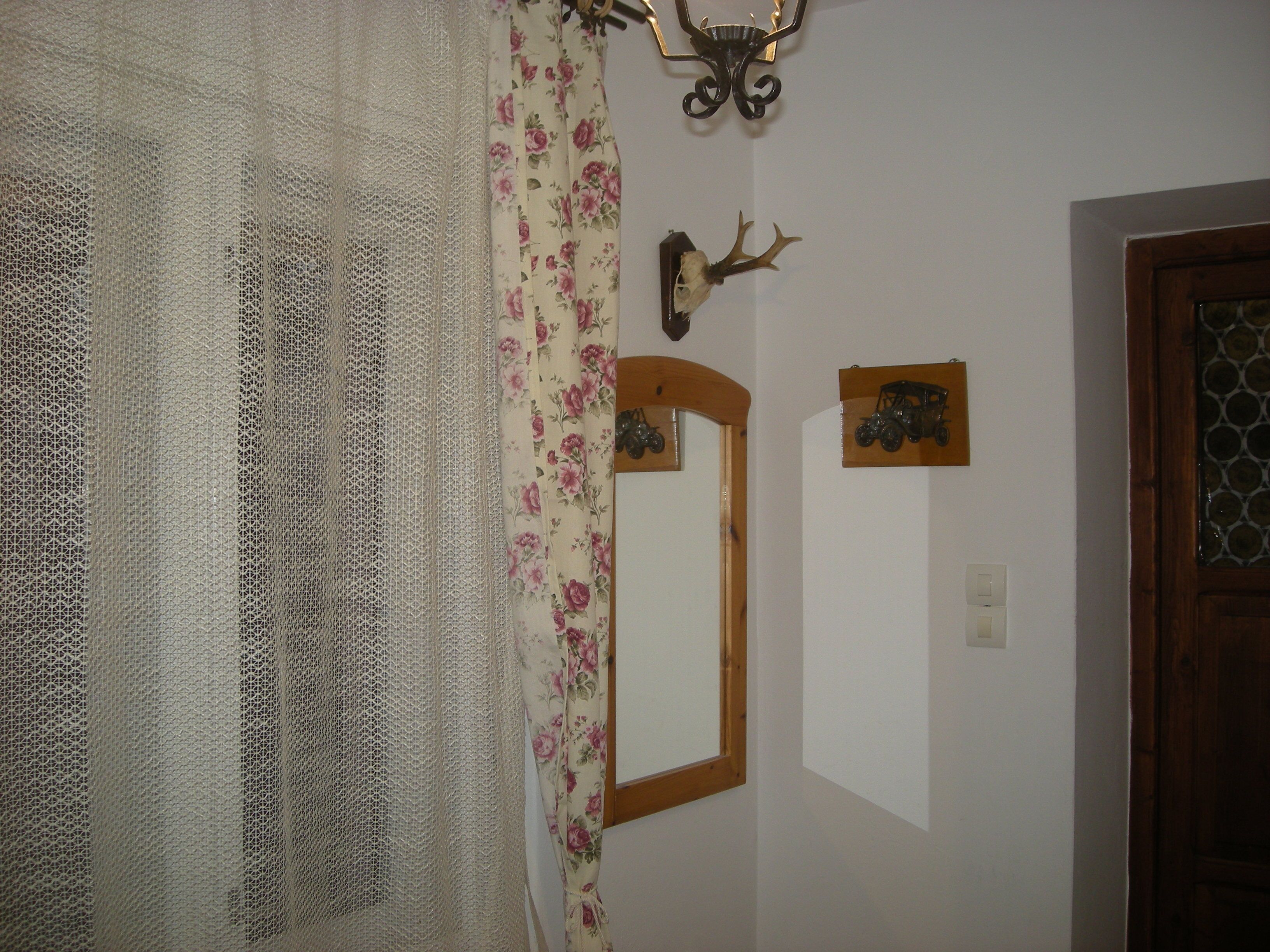 Ein Zimmer mit Holztür, Spiegel und einem Wandbild eines Hirschkopfes.