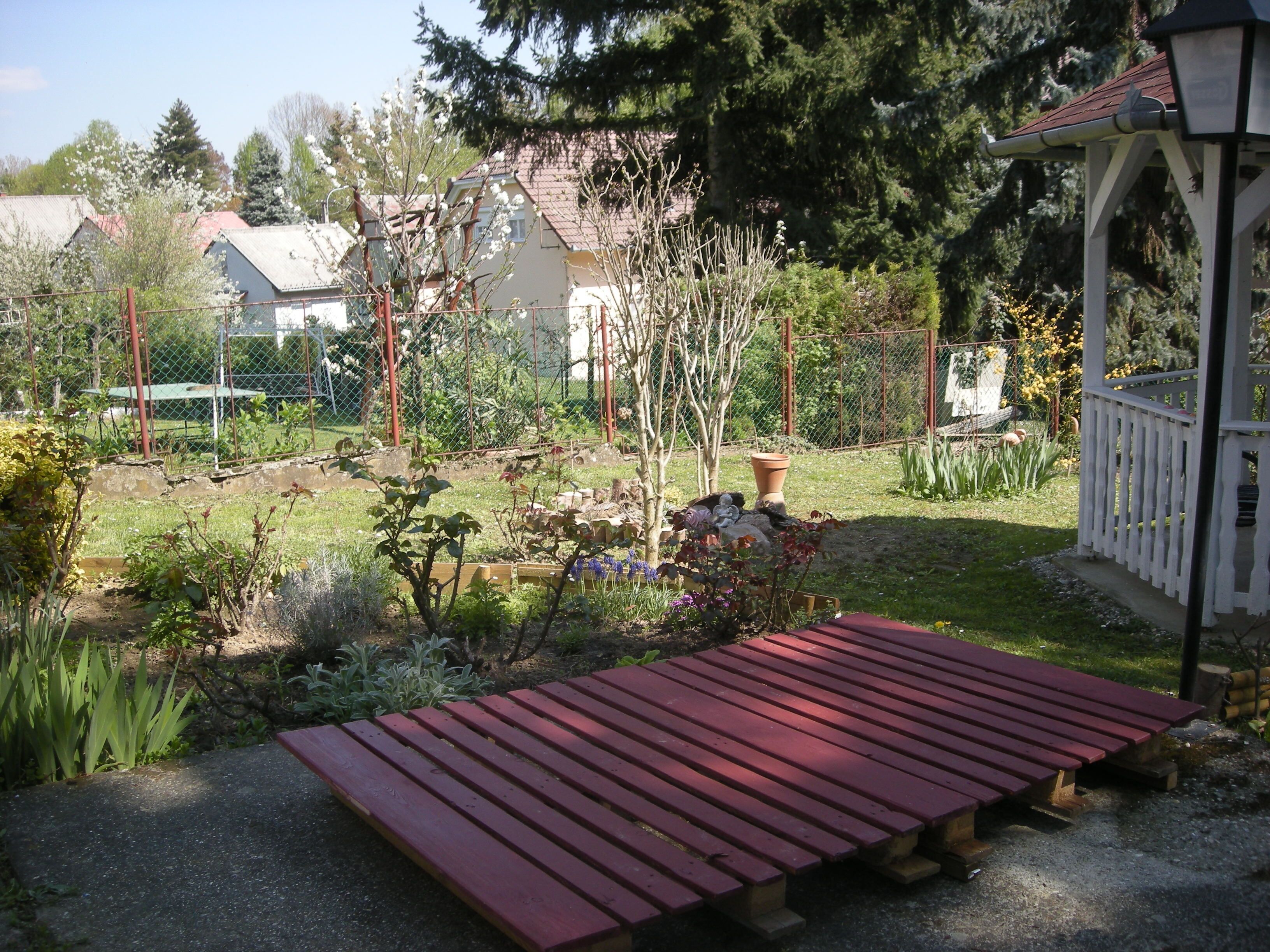 Un jardin agrémenté d’un banc en bois, d’un kiosque et de diverses plantes.