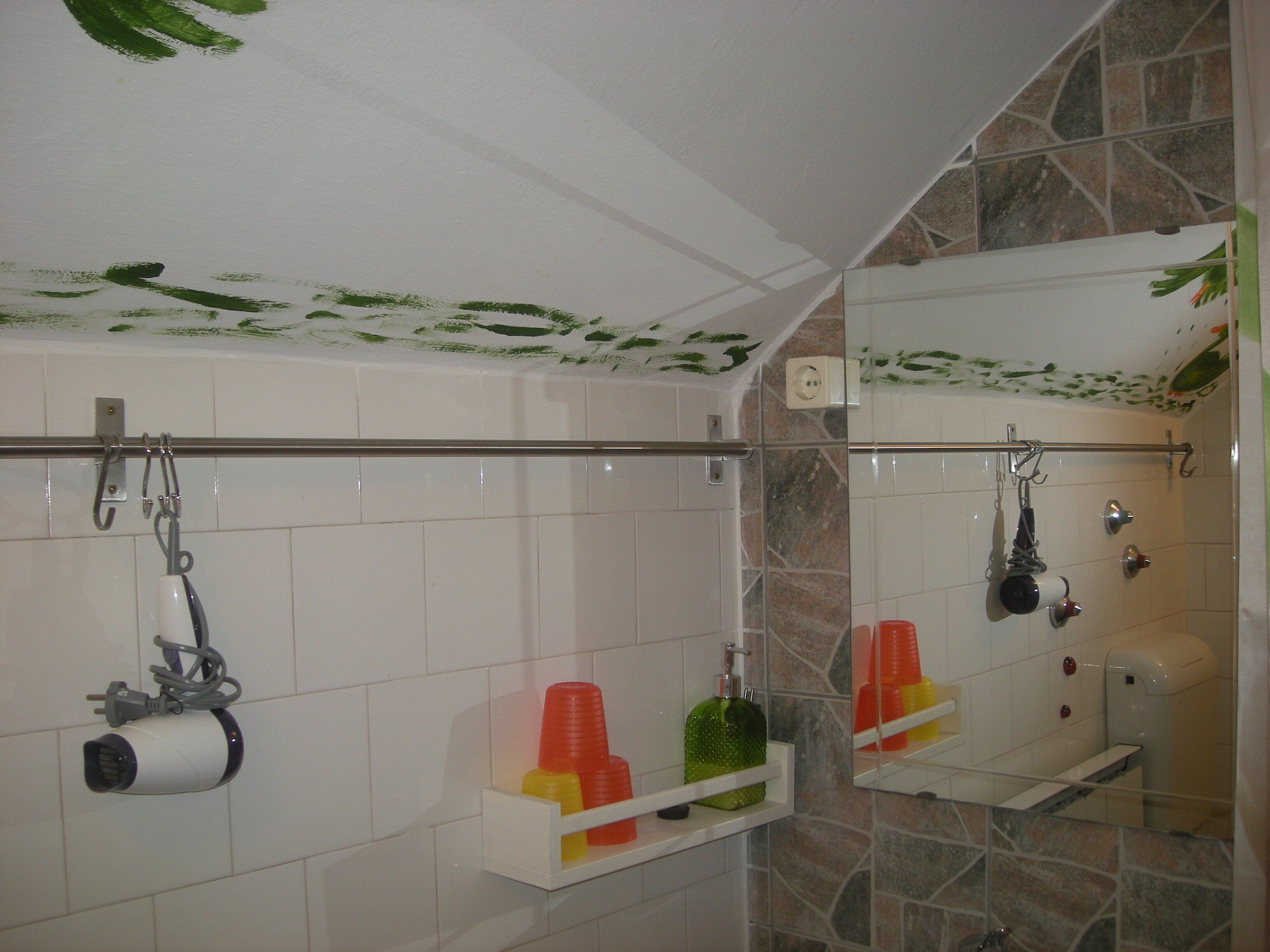 A bathroom with a shower, a toilet, and a sink. There are toiletries on the sink and a towel rack.