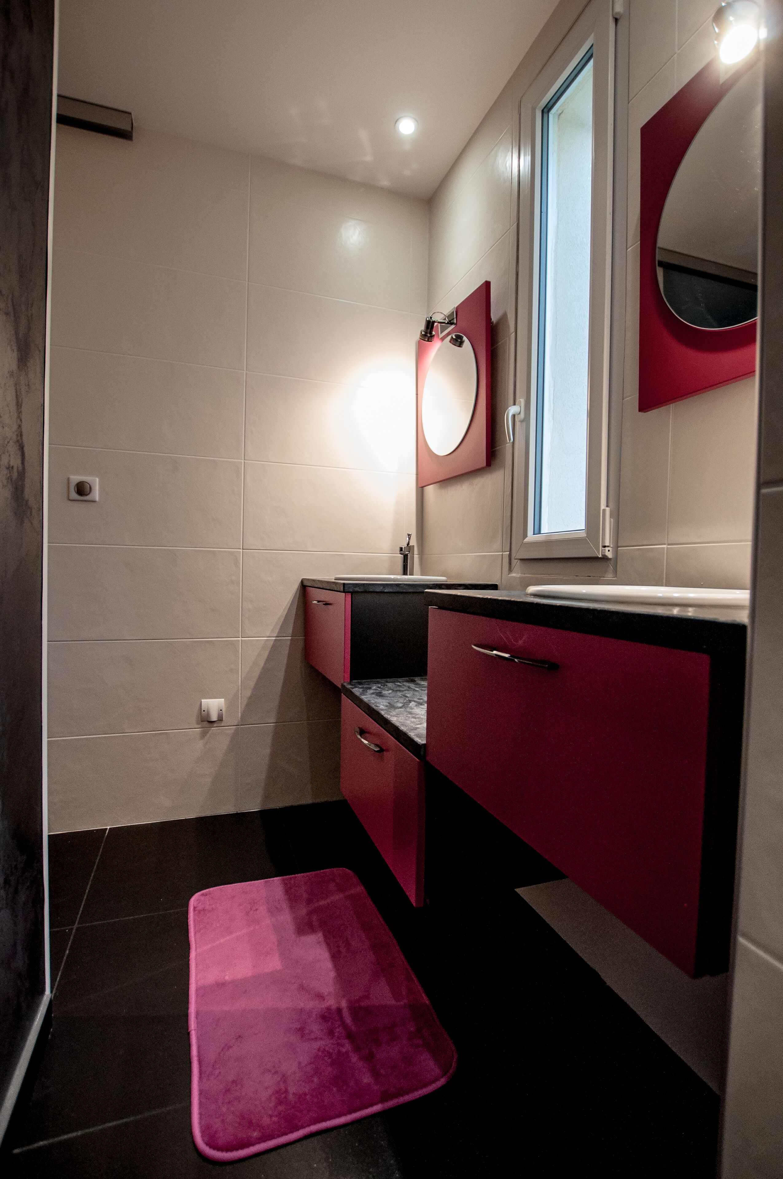 A modern bathroom with a vanity, mirror, and a pink bath mat.