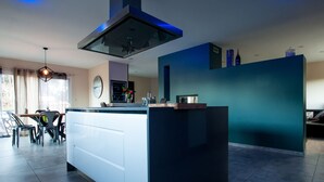 Una cocina moderna con una isla central, un comedor con sillas y un espacio de sala con un sofá.