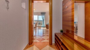 Un couloir avec un banc en bois, un téléphone et une vue sur une salle à manger avec une table et des chaises.