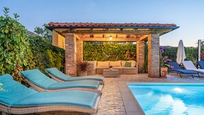 A pool area with lounge chairs, a covered seating area, and a brick wall. - APARTMENT 67 M2 - A BEDROOM, MODERN, COMFORTABLE LARGE BALCONY, BATH VIEW (Palit)