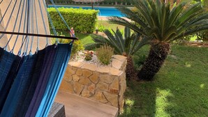 A hammock overlooking a pool, surrounded by lush greenery and a stone wall. - Very nice house with terrace and pool (Roda)