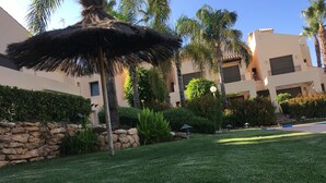 A well-maintained outdoor area with a thatched umbrella, palm trees, and a stone wall. - Very nice house with terrace and pool (Roda)