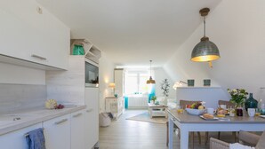 Una cuina moderna amb armaris blancs, una zona de dinar amb taula preparada per l'esmorzar i vista cap al saló.