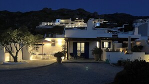 Edifici modern amb una entrada ben il·luminada, un arbre al primer pla i un paisatge de muntanyes al fons.