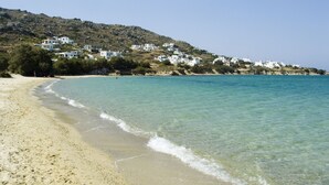 Una platja amb aigua turquesa cristal·lina, sorra daurada i edificis blancs en un turó.