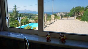 A window with a view of a pool and a distant landscape.