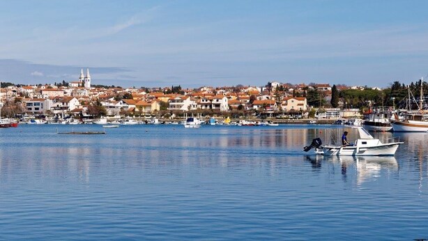 Une ville côtière dotée d’un port de plaisance, de bateaux et d’un clocher d’église imposant.