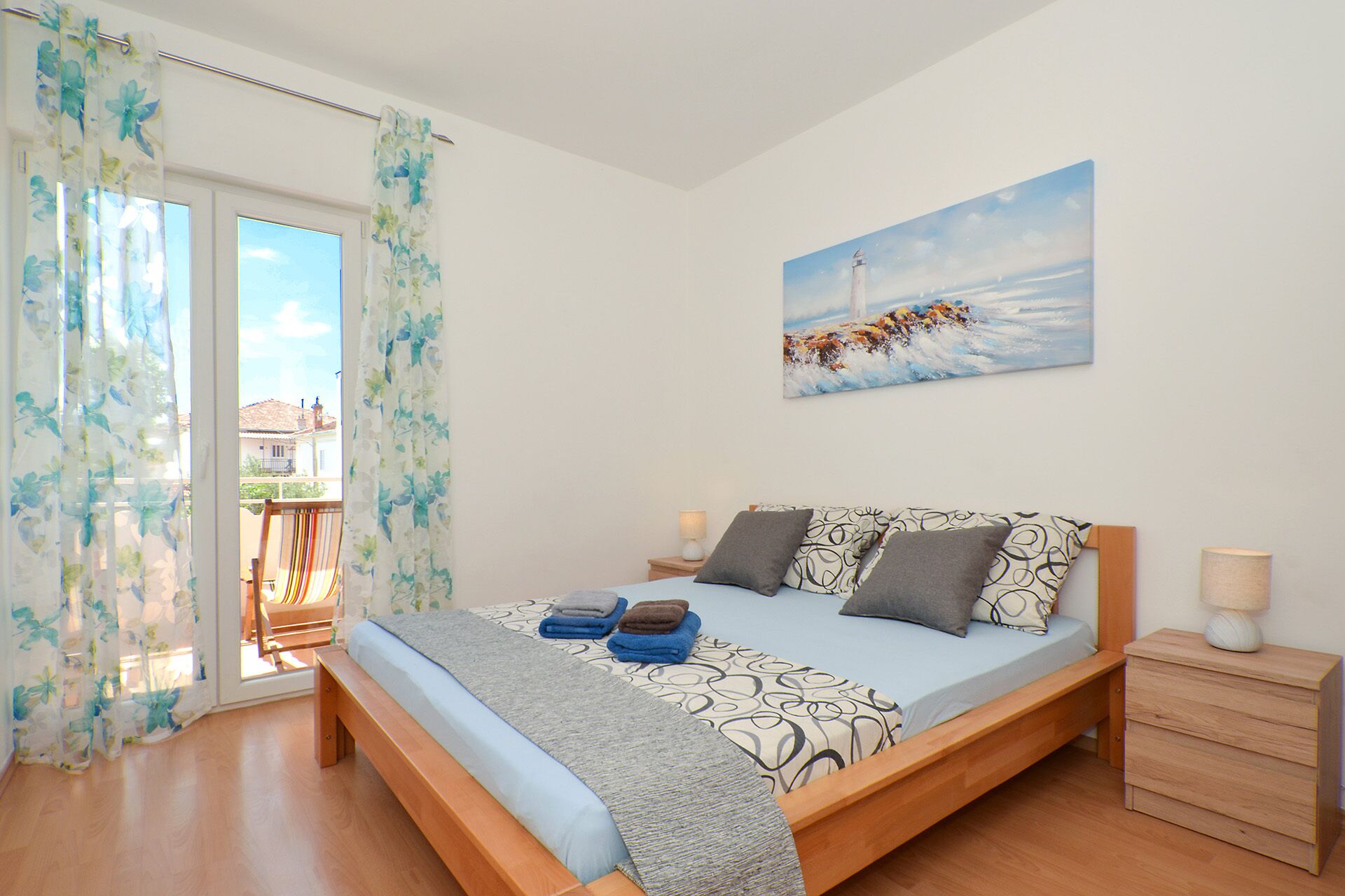 A bedroom with a bed, a nightstand, a lamp, and a painting on the wall.