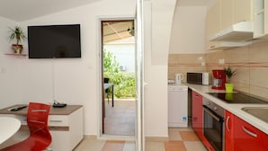 Une cuisine compacte avec un coin repas, un téléviseur fixé au mur et une vue sur l’extérieur.