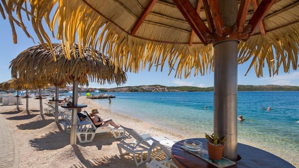 Une plage avec une eau cristalline, des chaises longues et des parasols.
