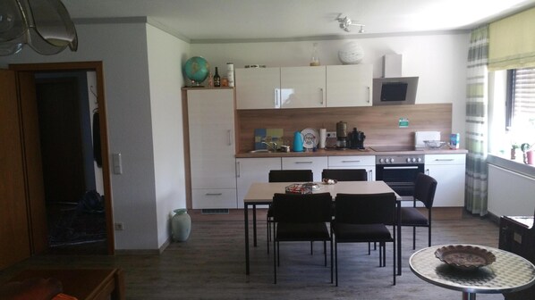 A compact kitchen with a dining area, including a table and chairs, a microwave, and a stove.