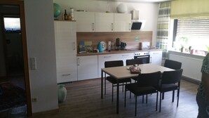 Et moderne køkken med hvide skabe, en træbordplade og et spiseområde med et bord og stole.